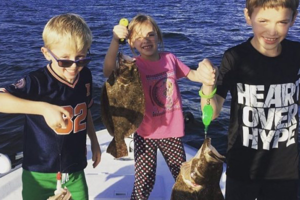 Kids holding up fish they just caught on a fishing boat